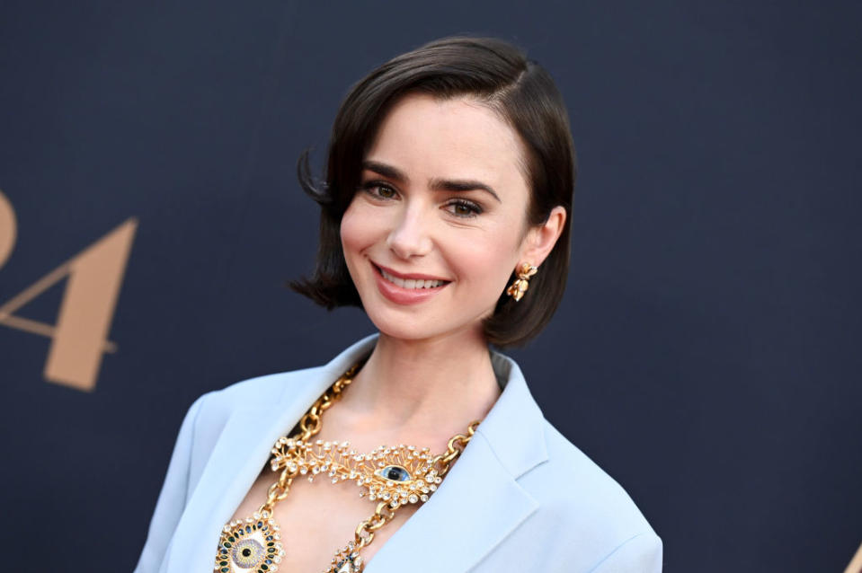 A woman in a light suit with an ornate necklace smiles at an event